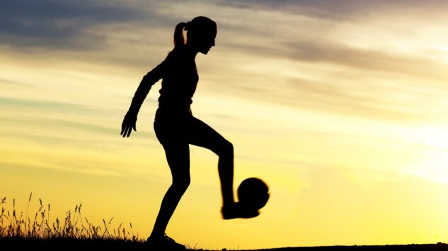 woman playing football at sunset
