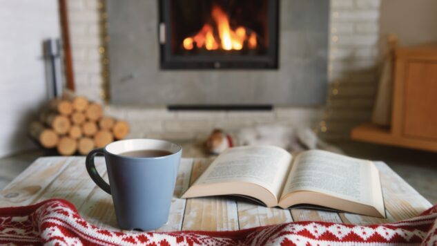 open book and cup of tea by fireplace
