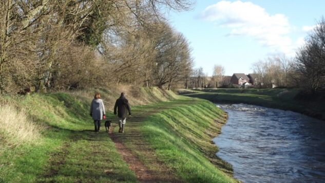 two people walking outside by riverbank