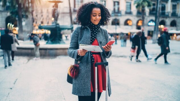 woman with map and phone in hand in city centre