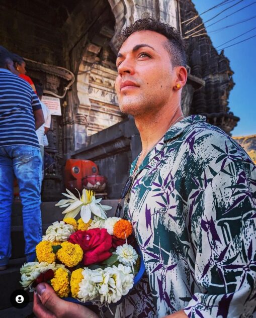 Rob Staines holding flowers looking away from the camera in a colourful shirt.
